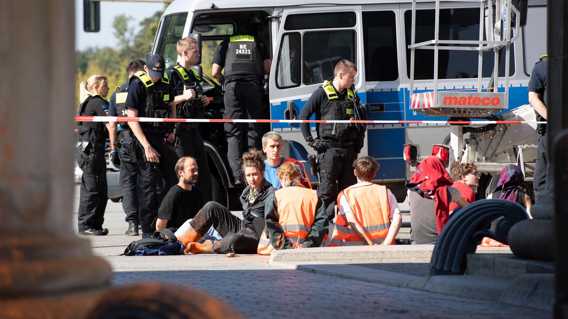 Polizeibeamte stehen am Brandenburger Tor um eine Gruppe festgesetzter Mitglieder der Klimaschutzgruppe Letzte Generation. Polizeibeamte stehen am Brandenburger Tor um eine Gruppe festgesetzter Mitglieder der Klimaschutzgruppe Letzte Generation.
