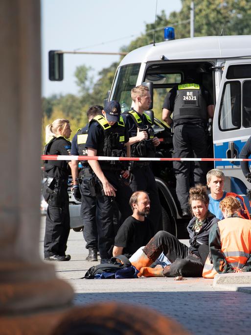Polizeibeamte stehen am Brandenburger Tor um eine Gruppe festgesetzter Mitglieder der Klimaschutzgruppe Letzte Generation. 