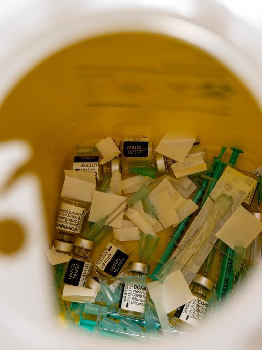 In einen Behälter sind verbrauchte Impfdosen und Spritzen entsorgt worden.