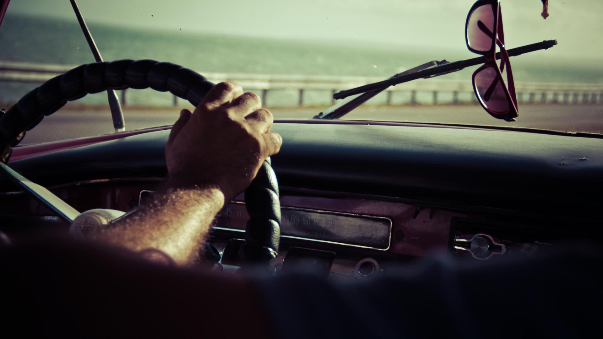 Ein Mann sitzt hinter dem Steuer und fährt eine Straße entlang.