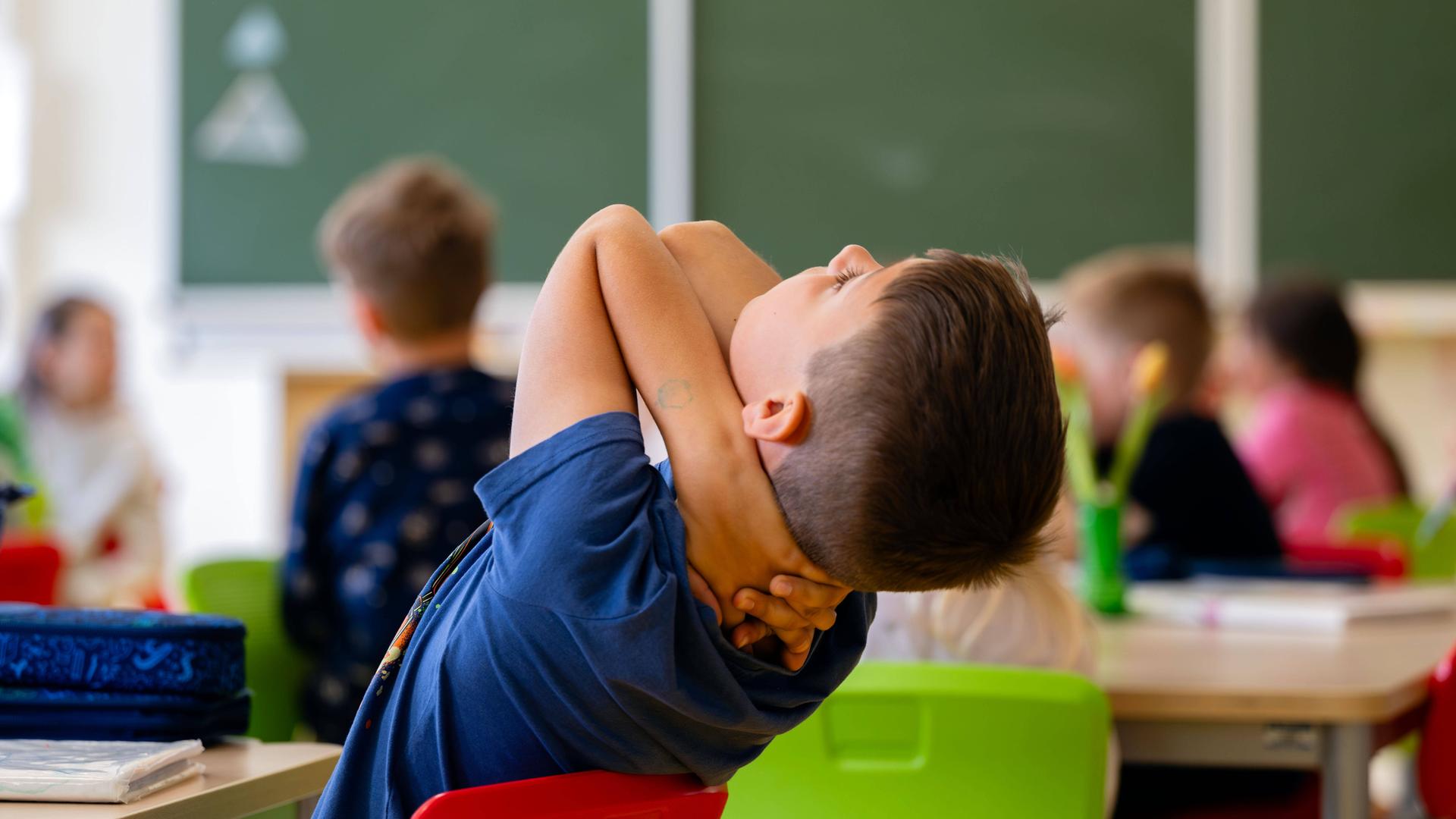 Ein Schüler in einem Klassenzimmer. Er beugt sich auf seinem Stuhl nach hinten. Seine Hände hat er im Nacken verschränkt. Ein Schüler in einem Klassenzimmer. Er beugt sich auf seinem Stuhl nach hinten. Seine Hände hat er im Nacken verschränkt.