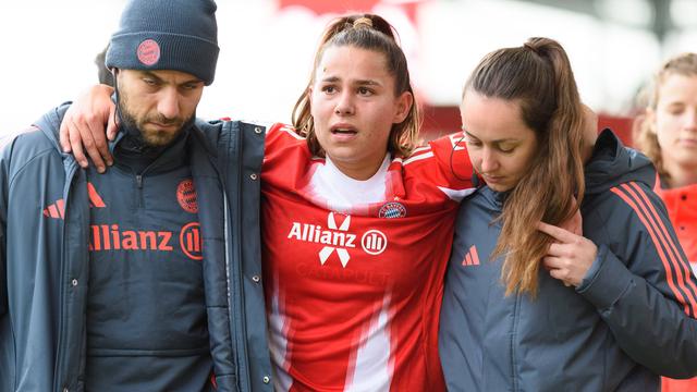 Lena Oberdorf im Trikot von Bayern München. Sie wird von einem Mann und einer Frau gestützt. Oberdorf weint.