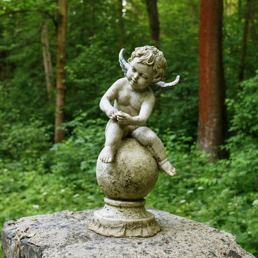 Ein kleiner sitzender Engel auf einem Friedhof.