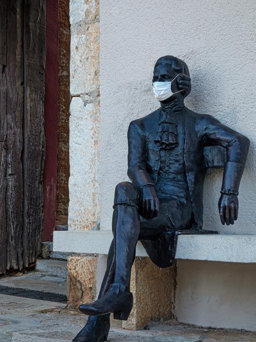 Eine Skulptur als Denkmal an Giacomo Casanova. Die Skulptur trägt eine medizinische Maske.