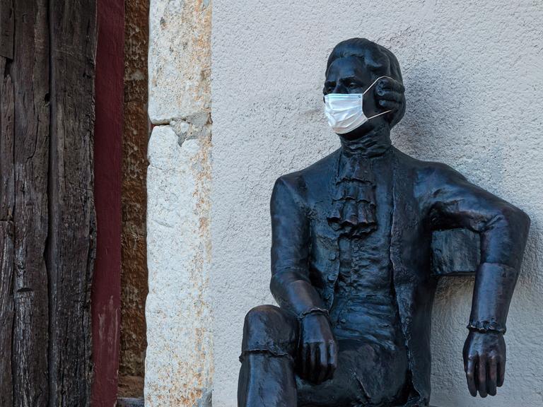 Eine Skulptur als Denkmal an Giacomo Casanova. Die Skulptur trägt eine medizinische Maske.