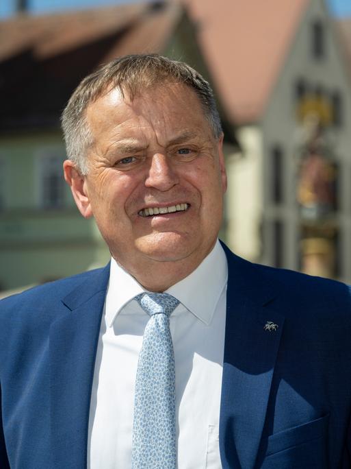 Richard Arnold trägt Sakko und Krawatte, steht am Rathaus und schaut direkt in die Kamera.