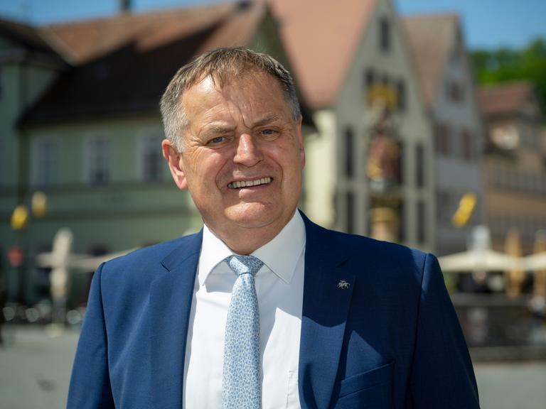 Richard Arnold trägt Sakko und Krawatte, steht am Rathaus und schaut direkt in die Kamera.