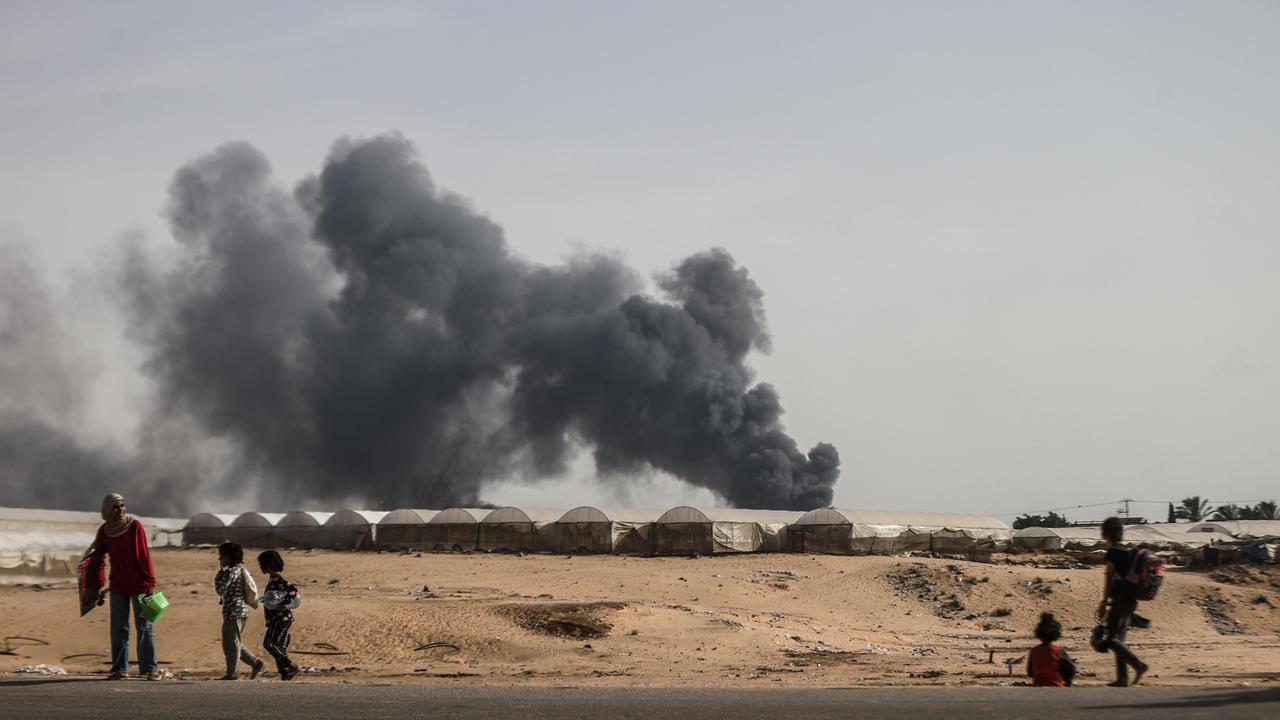 Zivilisten fliehen aus Rafah, im Hintergrund ist Rauch zu sehen