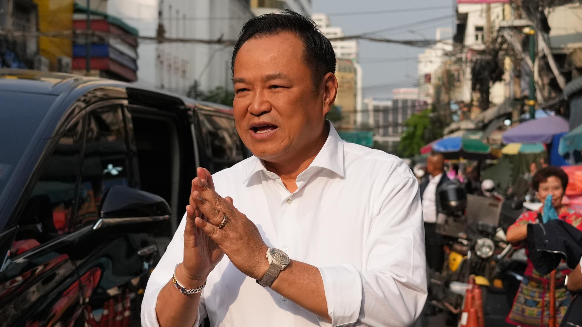 Thailands Regierungschef Anutin steht am Rand einer Straße und hält die Hände  vor der Brust aneinander.