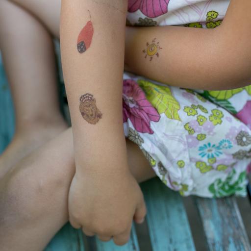 Ein kleines Mädchen trägt Klebetattoos am Arm.