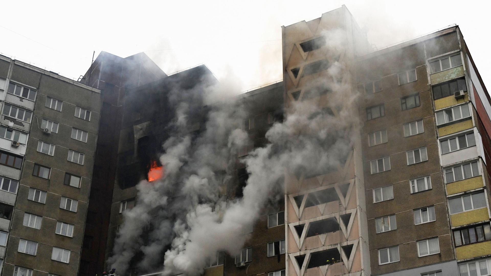 Ukraine, Kiew: Nach einem russischen Angriff tritt Feuer in eine Wohnblock aus mehreren Fenstern aus. 