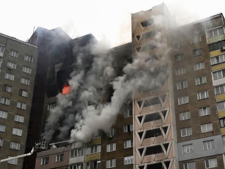 Ukraine, Kiew: Nach einem russischen Angriff tritt Feuer in eine Wohnblock aus mehreren Fenstern aus. 