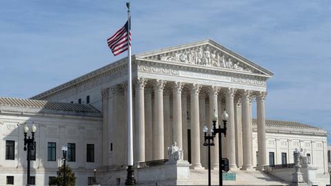 Außenansicht des U.S. Supreme Court: ein großes, weißes Gerichtsgebäude mit vielen Säulen und einer US-Flagge davor