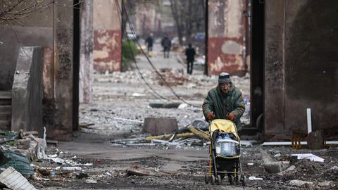 Im völlig zerstörten Mariupol schiebt ein Mann einen Kinderwagen und transportiert damit Plastikflaschen.