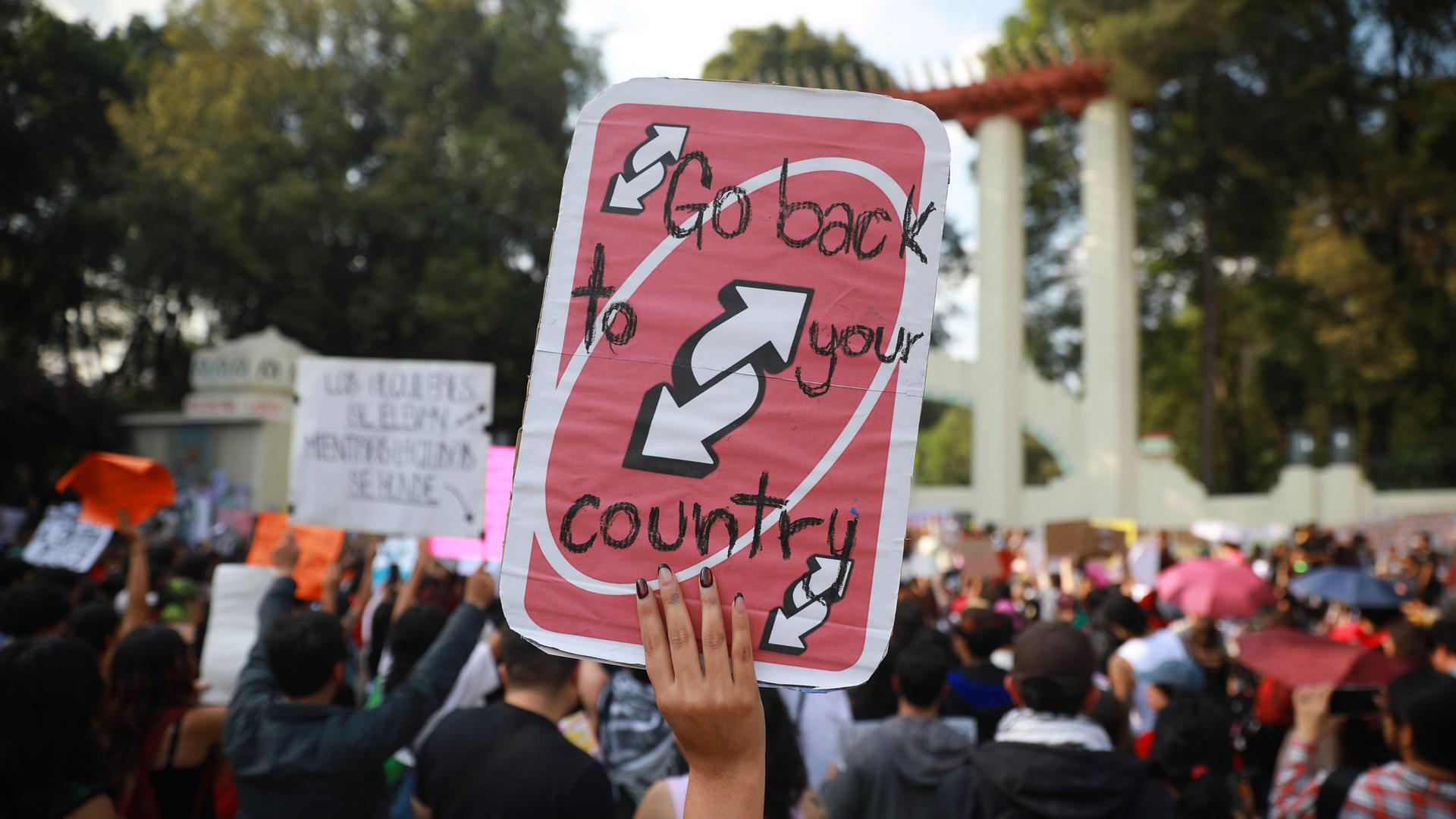 Bei einer Demonstration wird ein Schild mit der Aufschrift "Go back to your country" hochgehalten.