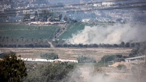 Zu sehen sind mehrere Felder im Gazastreifen, an einem Hang im Hintergrund steigt Rauch auf.
