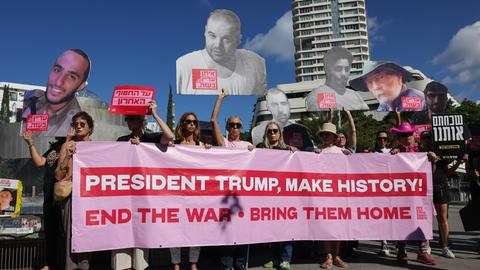 Menschen halten während einer Kundgebung in Tel Aviv zum zweiten Jahrestag der Hamas-Angriffe ein Transparent und Porträts von Geiseln hoch. 