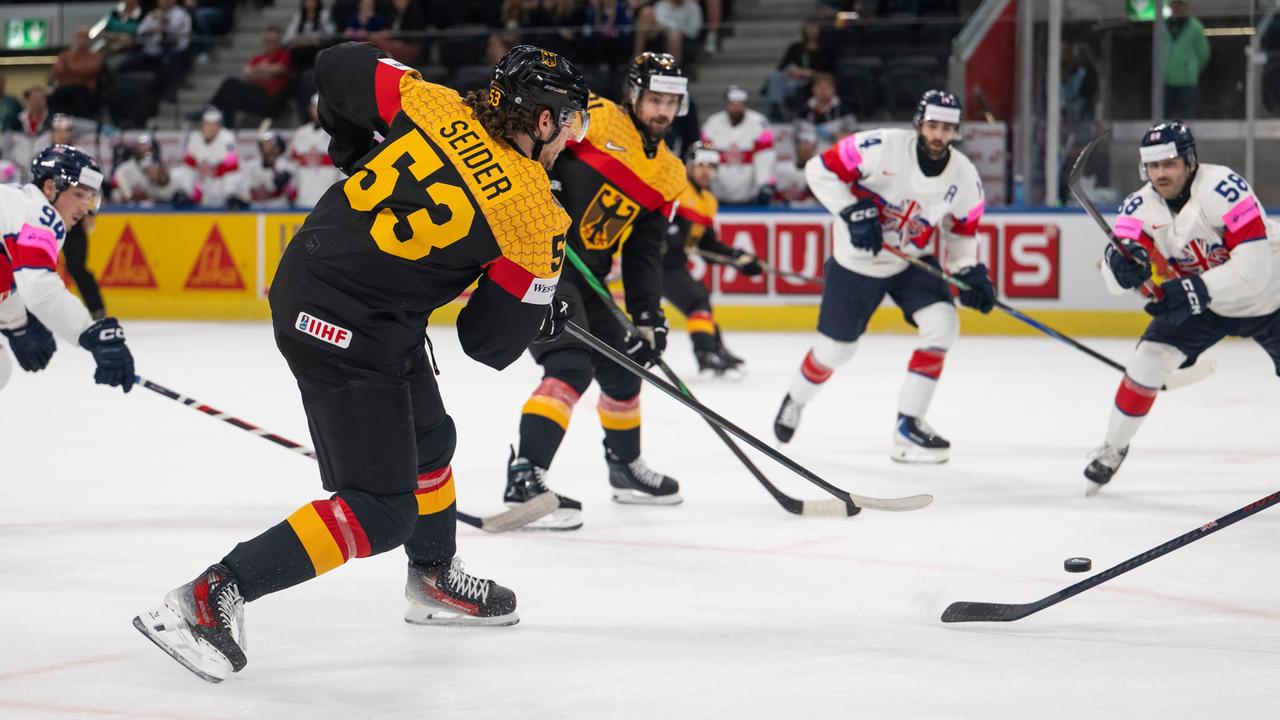 Mehrere Eishockey-Spieler mit deutschen und und britischen Trikots kämpfen bei einem Spiel um den Puck.