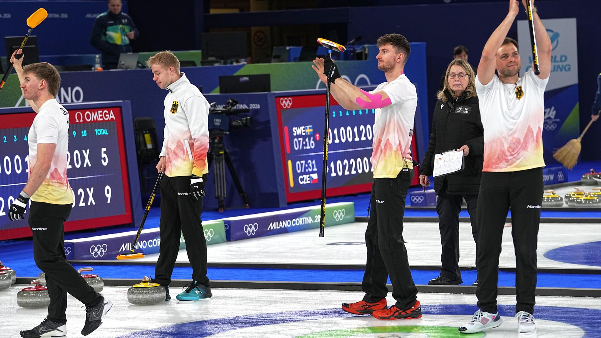Die vier Spieler des Curling-Teams applaudieren den Zuschauern.