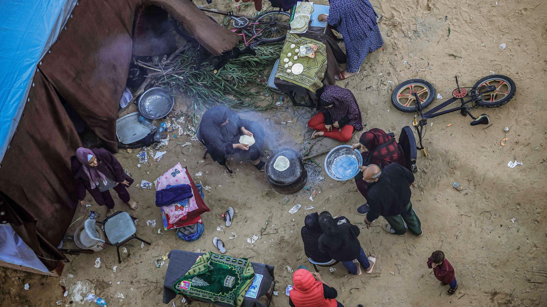 Eine Luftaufnahme zeigt behelfsmäßige Zeltlager in Rafah im südlichen Gazastreifen, in denen Palästinenser untergebracht sind. Sie kochen gemeinsam auf einem Feuer.