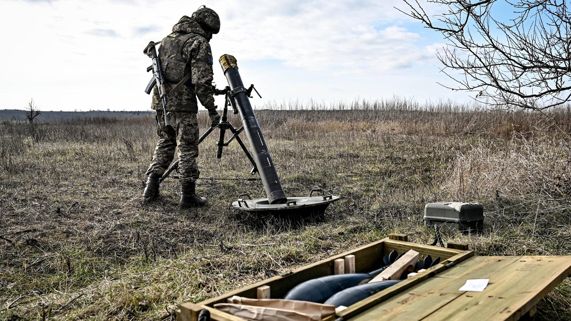 Ein ukrainischer Soldat bedient einen Mörser, im Vordergrund liegt Munition.