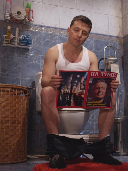 Ein Mann ist auf einem Klo und liest ein Magazin. Es ist der Schauspieler Wolodymyr Selenskyj, der später zum Präsident der Ukraine wurde.