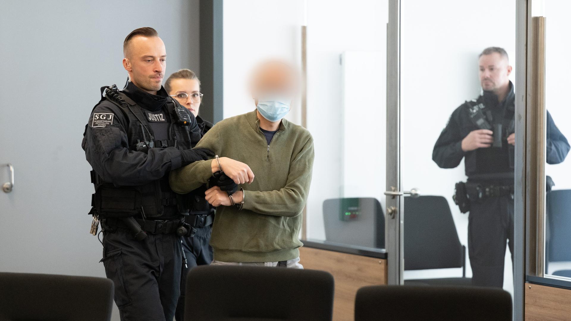 Der Hauptangeklagte Jian G. (M) wird vor Prozessbeginn in den Gerichtssaal geführt. 