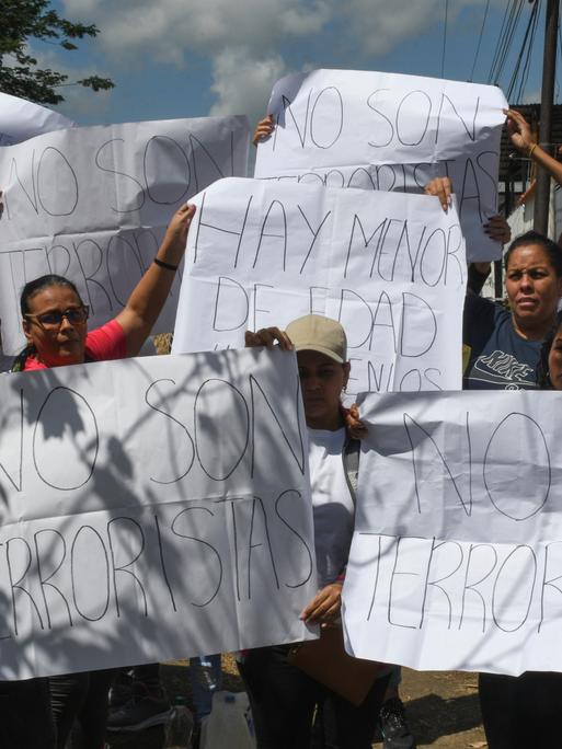 Menschen halten vor einem Gefängnis Plakate hoch. Darauf Aufschriften wie: "Gerechtigkeit" oder "Sie sind keine Terroristen". Menschen halten vor einem Gefängnis Plakate hoch. Darauf Aufschriften wie: "Gerechtigkeit" oder "Sie sind keine Terroristen".