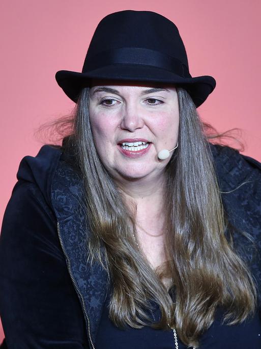 Tanya Stewner spricht bei der Frankfurter Buchmesse 2025 auf einer Bühne vor einem roten Hintergrund in ein Mikrofon. Sie trägt einen schwarzen Hut. Tanya Stewner spricht bei der Frankfurter Buchmesse 2025 auf einer Bühne vor einem roten Hintergrund in ein Mikrofon. Sie trägt einen schwarzen Hut.