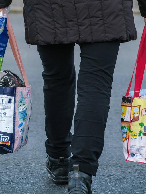 Düsseldorf 11.11.2022: Ein Mensch trägt Einkäufe in Plastiktaschen.