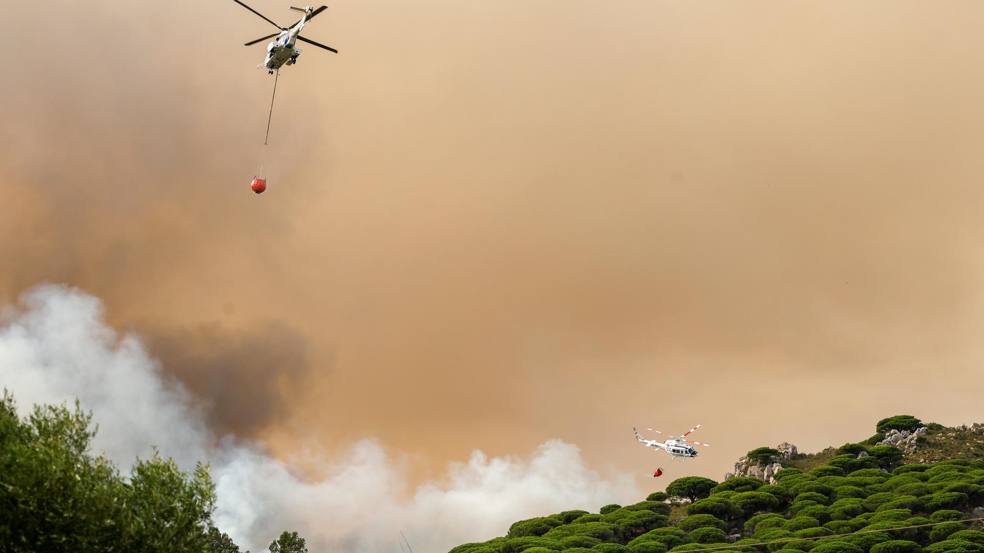Löschhubschrauber über einem brennenden Waldgebiet