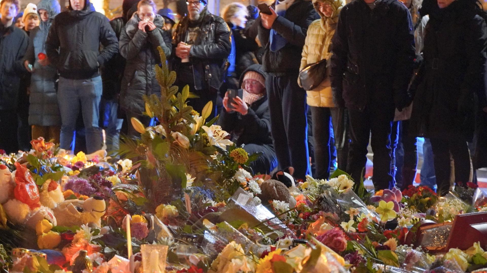 Menschen stehen vor einem Meer aus Blumen und gedenken der Toten des Magdeburger Terranschlags