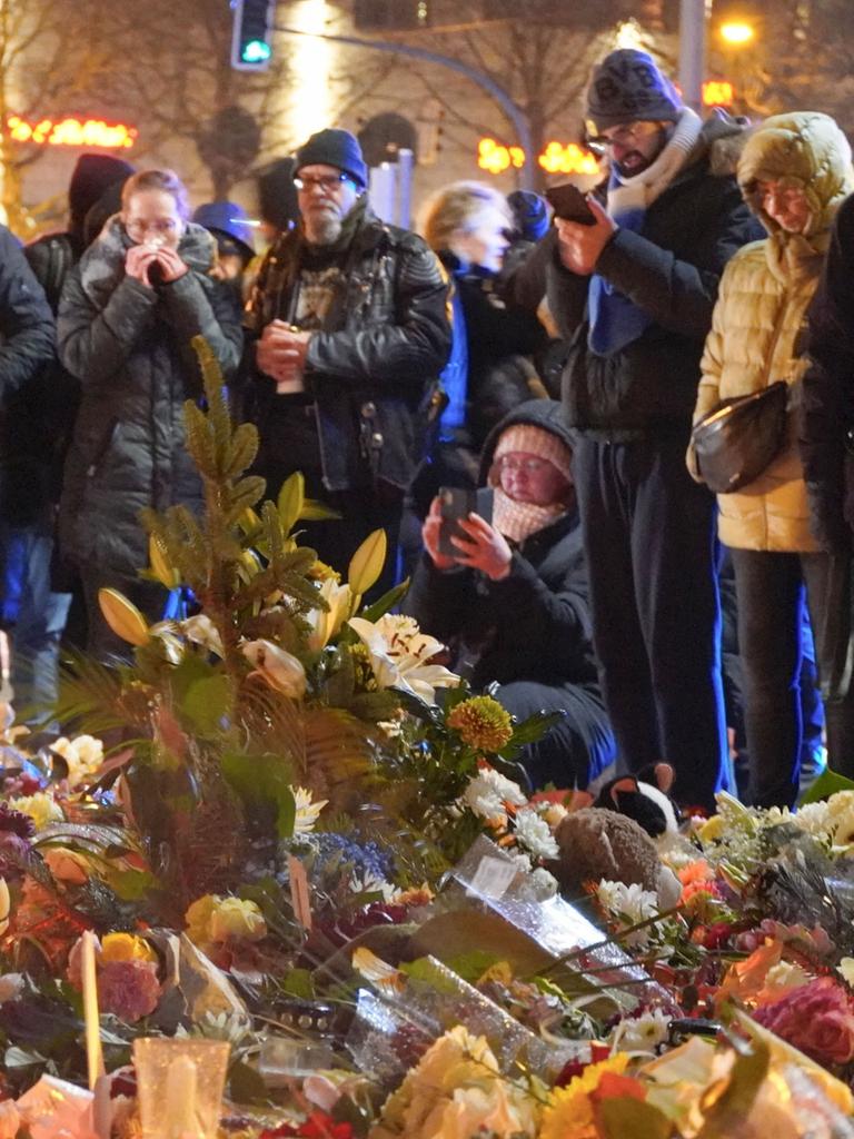 Menschen stehen vor einem Meer aus Blumen und gedenken der Toten des Magdeburger Terranschlags