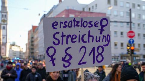 Demonstration am Internationalen Frauentag in Augsburg: Eine Frau trägt ein Schild mit der Aufschrift "Ersatzlose Streichung § 218". Das ist der Pragraph im deutschen Strafrecht zum Schwangerschaftsabbruch.