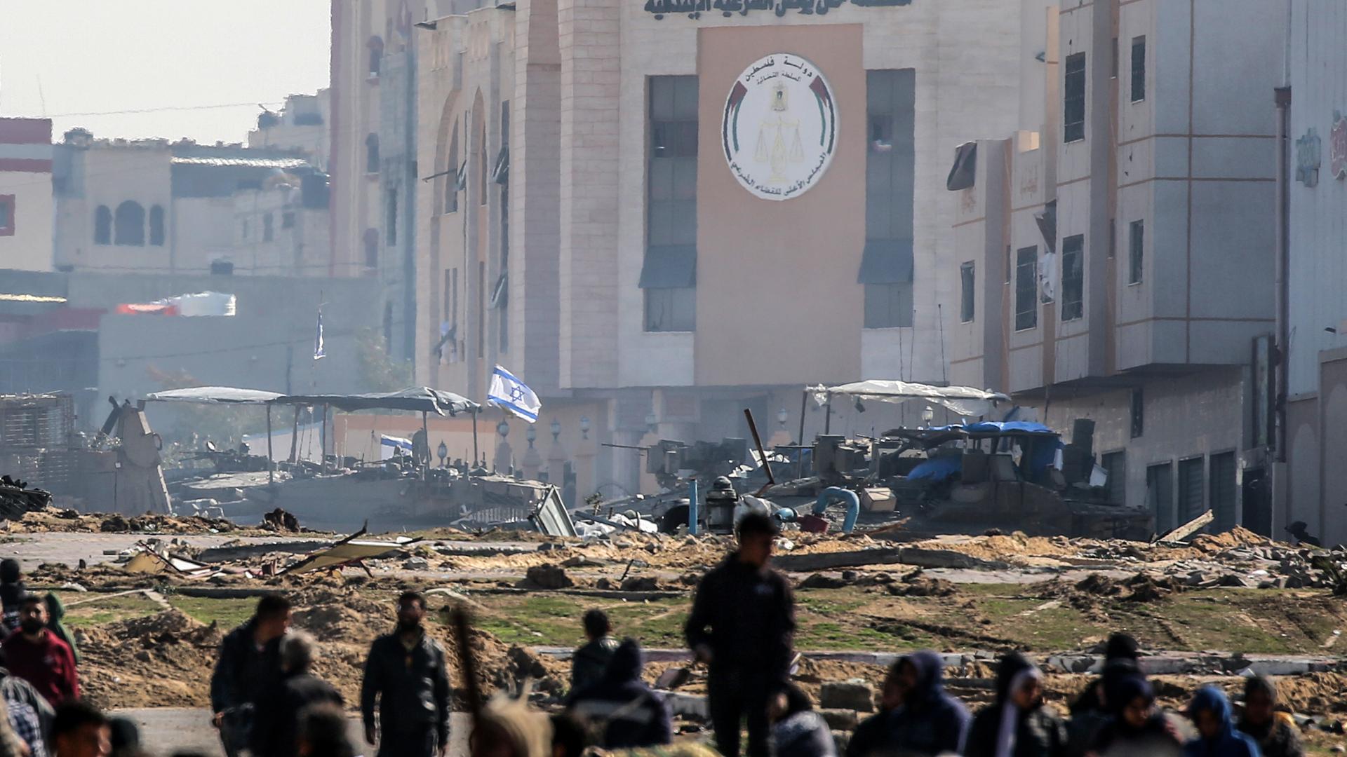 Israelische Panzer rollen an beschädigten Gebäuden in der Stadt Chan Junis im Gazastreifen entlang, während Palästinenser durch den westlichen Ausgang der Stadt in sicherere Gebiete fliehen.