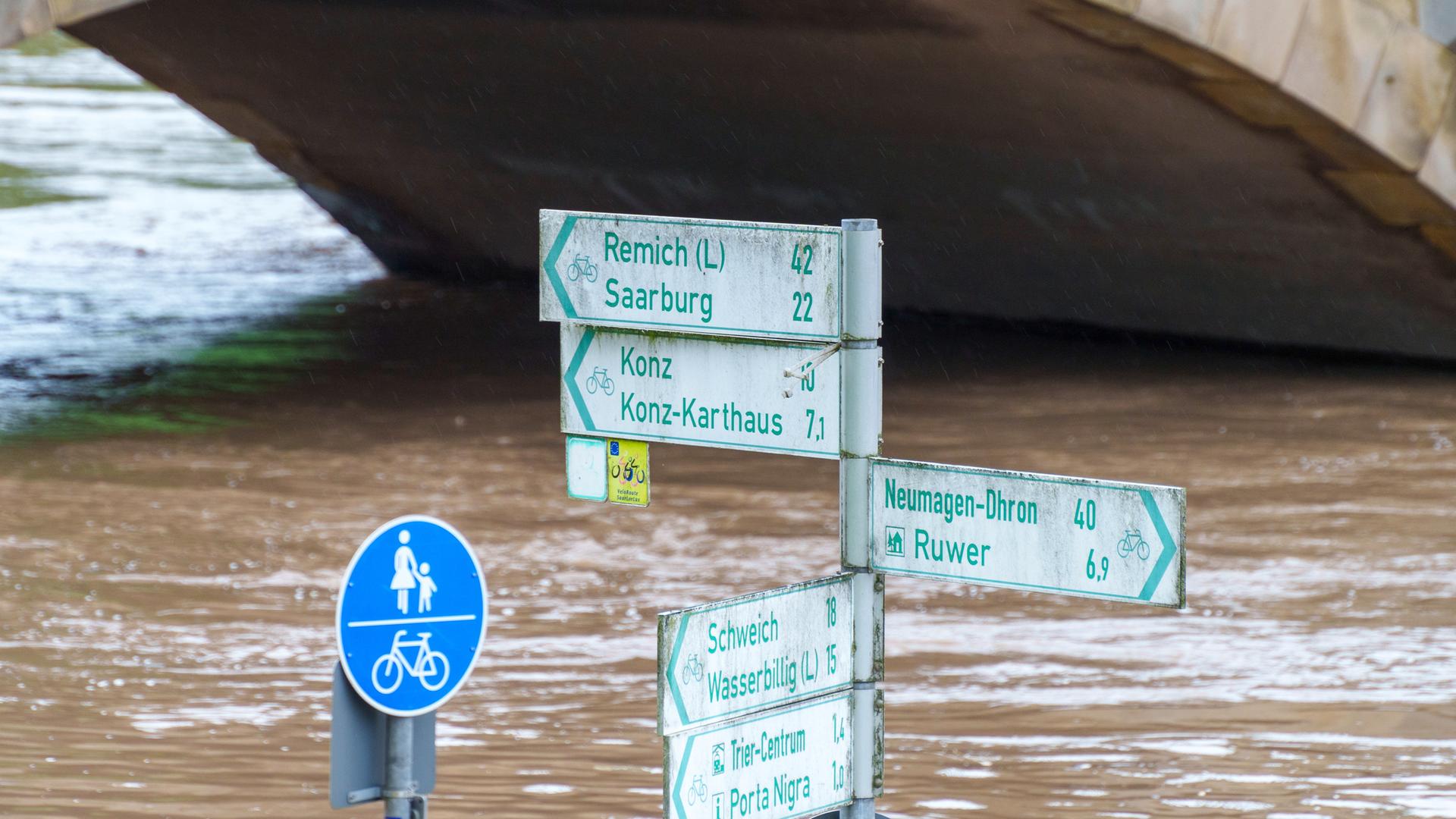 Radwegeschilder stehen am Zurlaubener Ufer im Moselhochwasser. Für Trier hatte der Deutsche Wetterdienst am 18. Mai 2024 die höchste Warnstufe vergeben.