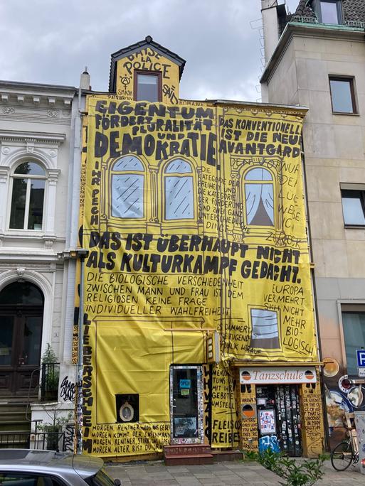 Die Buchhandlung "Golden Shop" hat ihre Fassade neu gestaltet. Auf gelbe Stoffbahnen sind Zitate von Kulturstaatsminister Weimer gedruckt, der den Laden von der Liste der Preisträger für den Deutschen Buchhandlungspreis 2026 gestrichen hatte. 