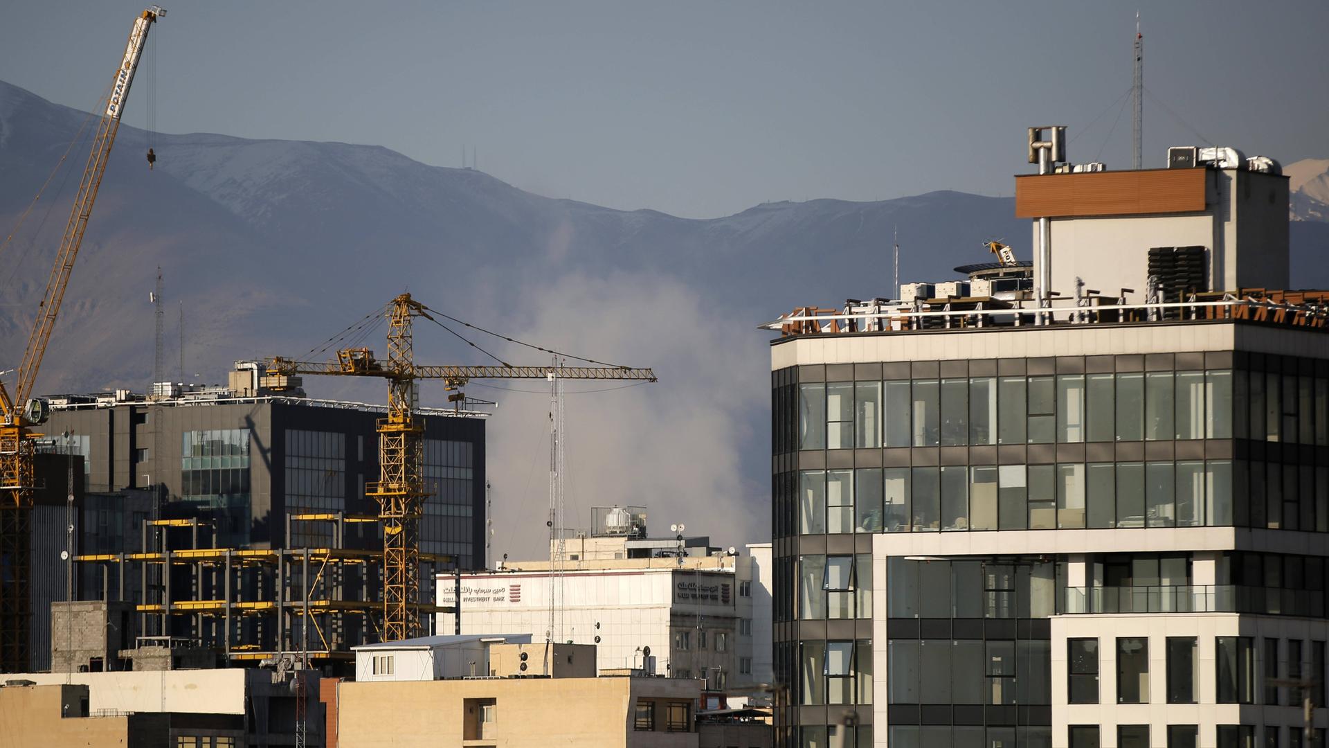 Zwischen mehreren hohen Gebäuden in der iranischen Hauptstadt Teheran steigt eine Rauchwolke auf. 