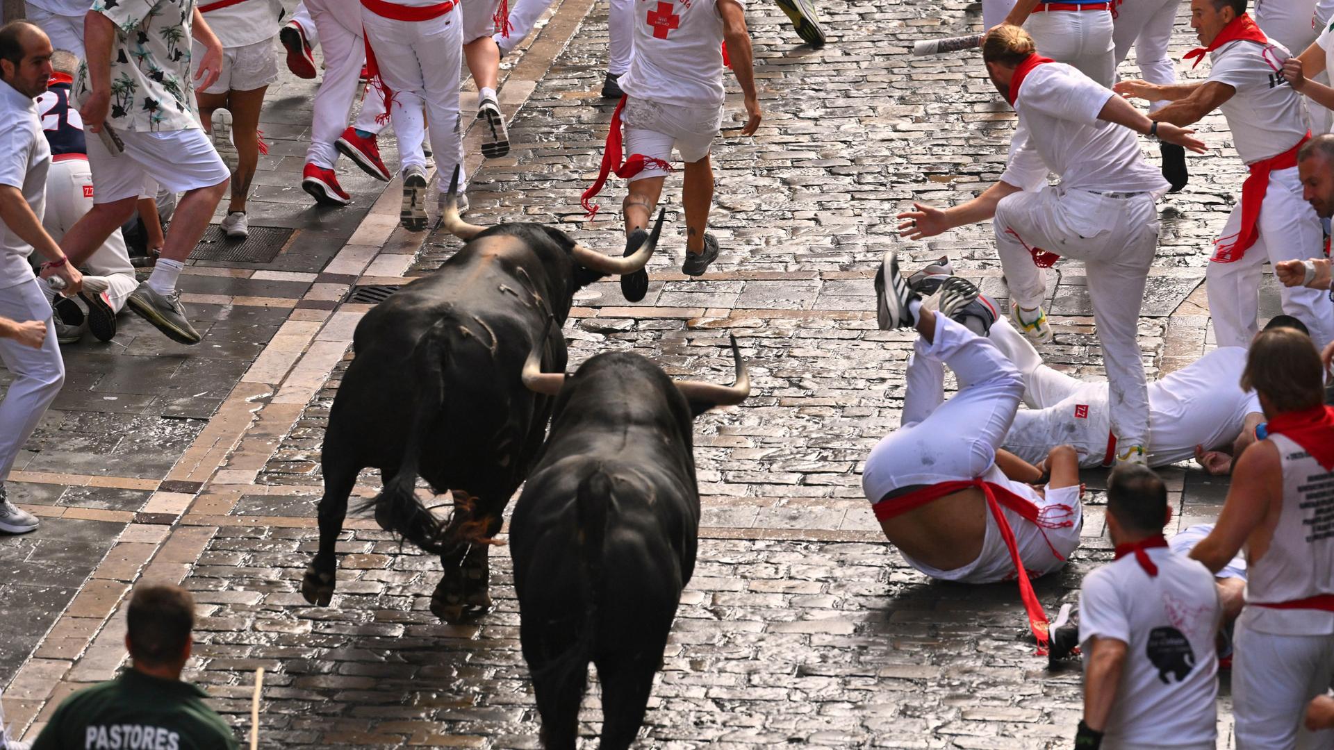 Schaulustige laufen mit den Stieren der Fuente Ymbro Ranch während des ersten Tages des Stiertreibens bei den San Fermín Fiestas in Pamplona.
