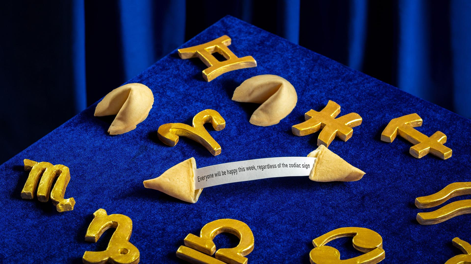 Sternzeichensymbole und Gleckskekse sind auf einem samtig blauen Hintergrund arrangiert.