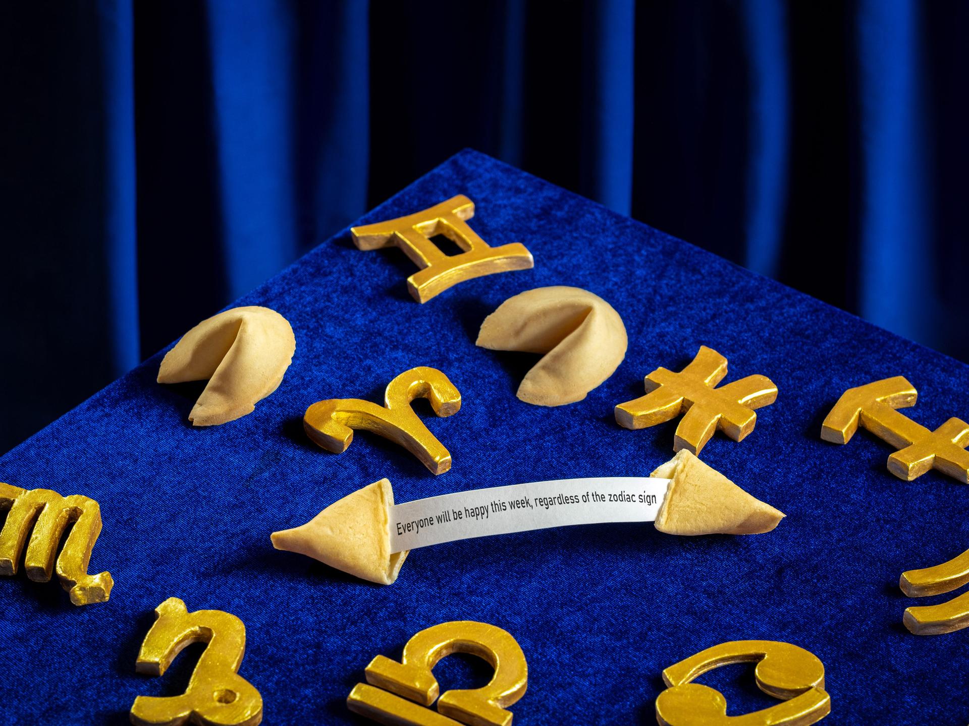 Sternzeichensymbole und Gleckskekse sind auf einem samtig blauen Hintergrund arrangiert.