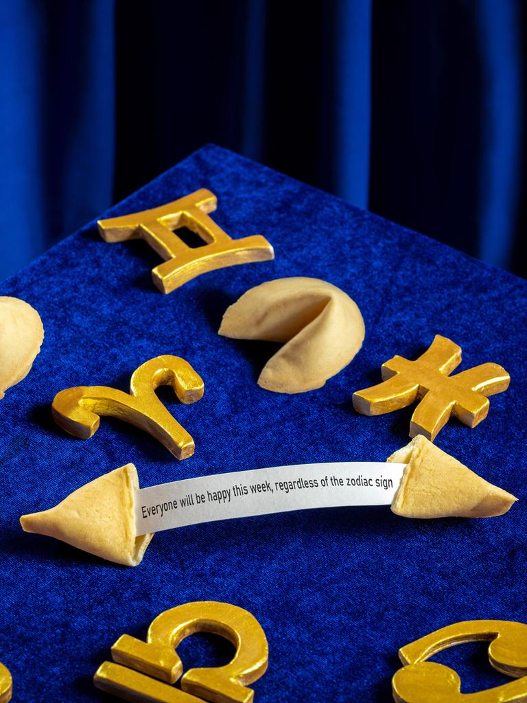 Sternzeichensymbole und Gleckskekse sind auf einem samtig blauen Hintergrund arrangiert.