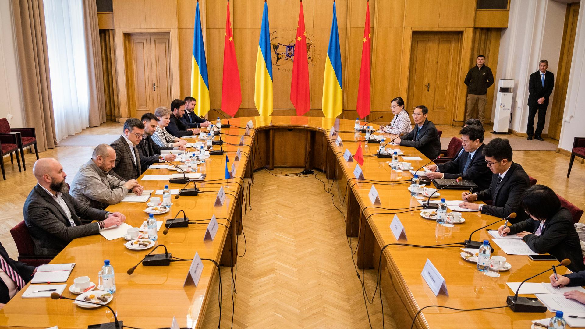 Ukraine, Kiew: Der russische Außenminister Dmytro Kuleba, in der Mitte links und der chinesiche Sondergesandte Li Hui, in der Mitte rechts, sitzen an einem großen Tisch mit mehreren Personen.