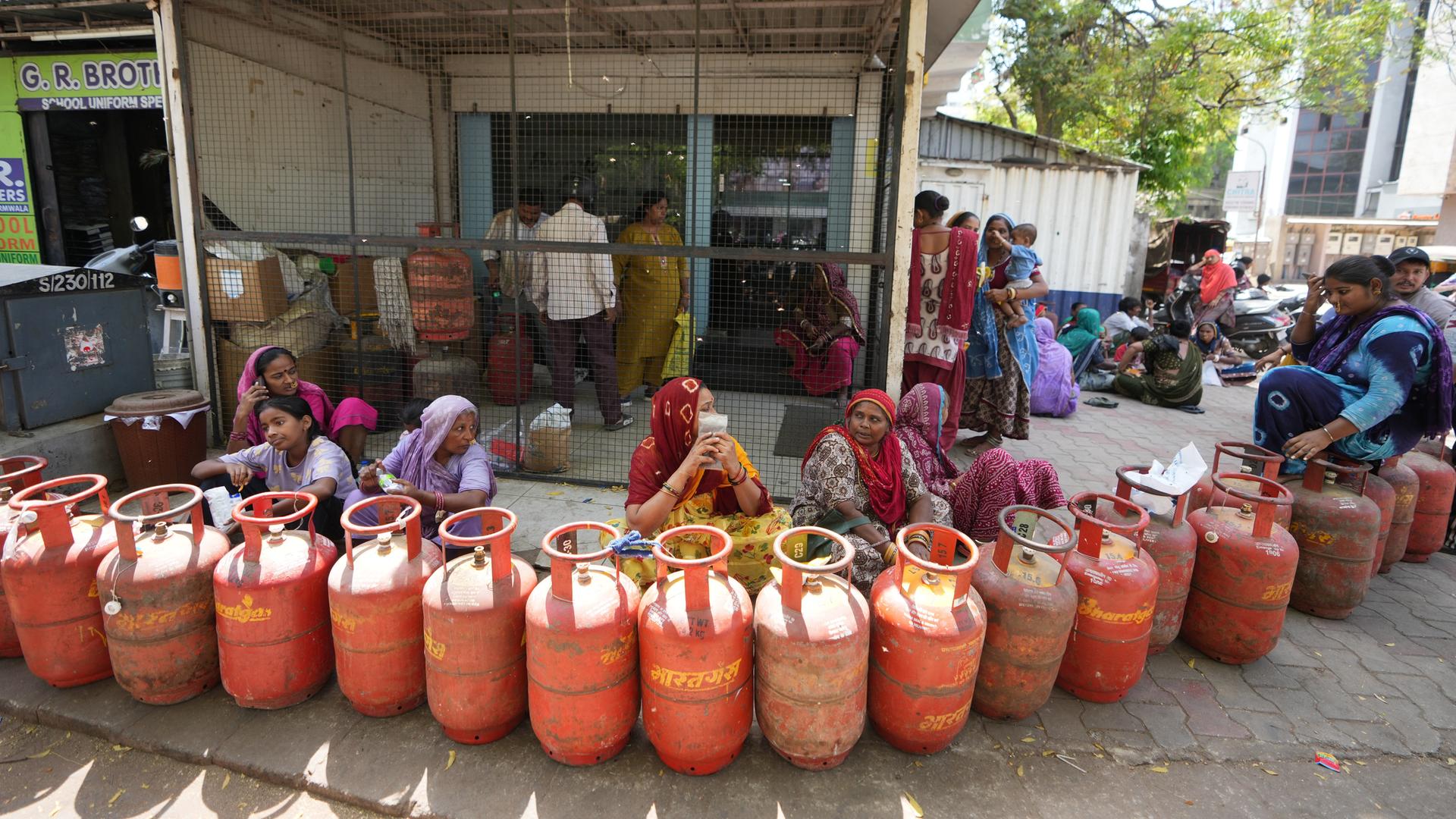 Menschen warten auf die Abholung von Flüssiggasflaschen bei einem autorisierten Händler in Ahmedabad in Indien.