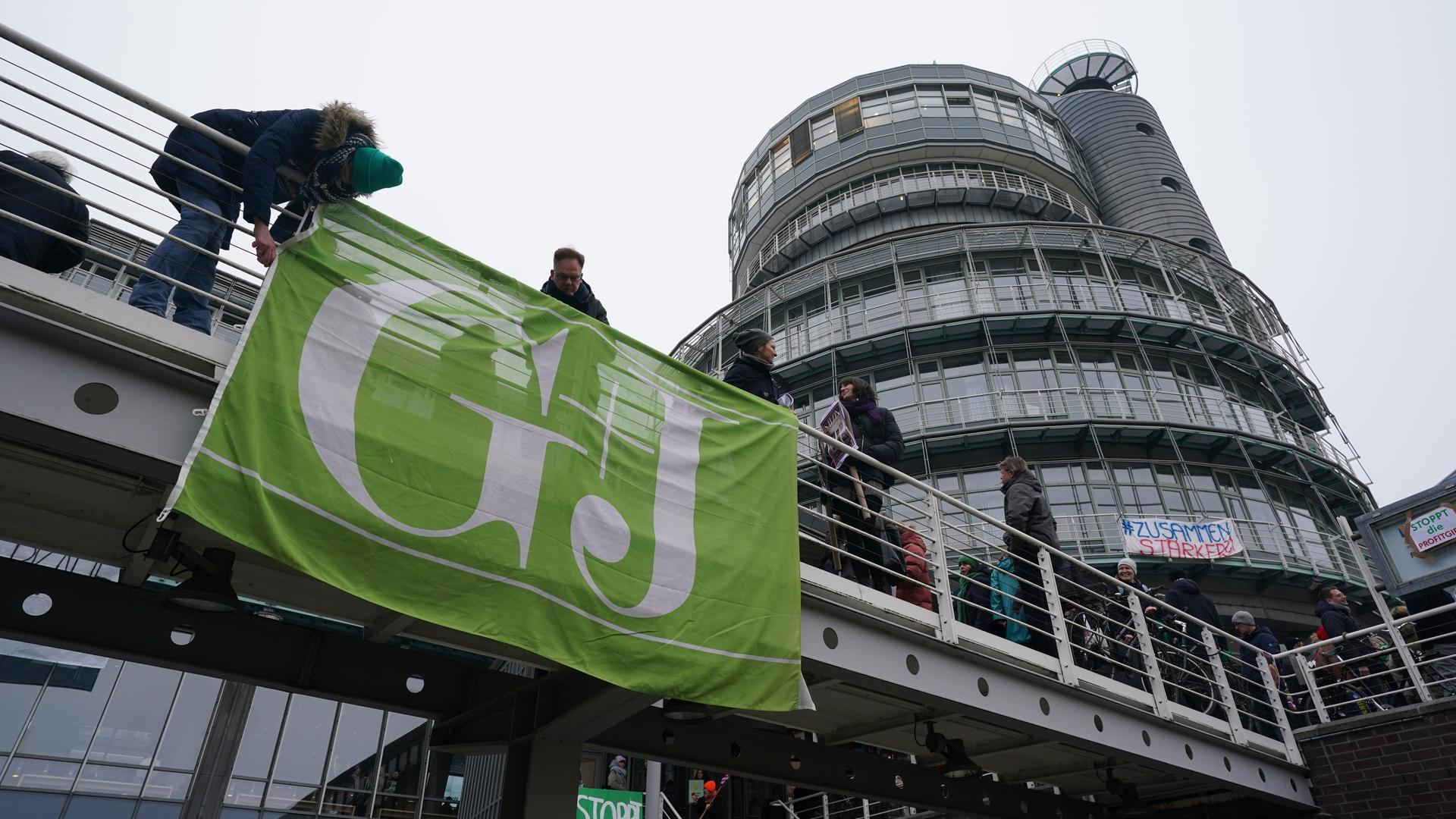Mitarbeiterinnen und Mitarbeiter von RTL Deutschland hängen eine Flagge mit dem Logo des Gruner+Jahr-Verlags nach einer "aktiven Mittagspause" vor dem Verlagsgebäude am Baumwall gegen Verkäufe der Zeitschriften ab. 