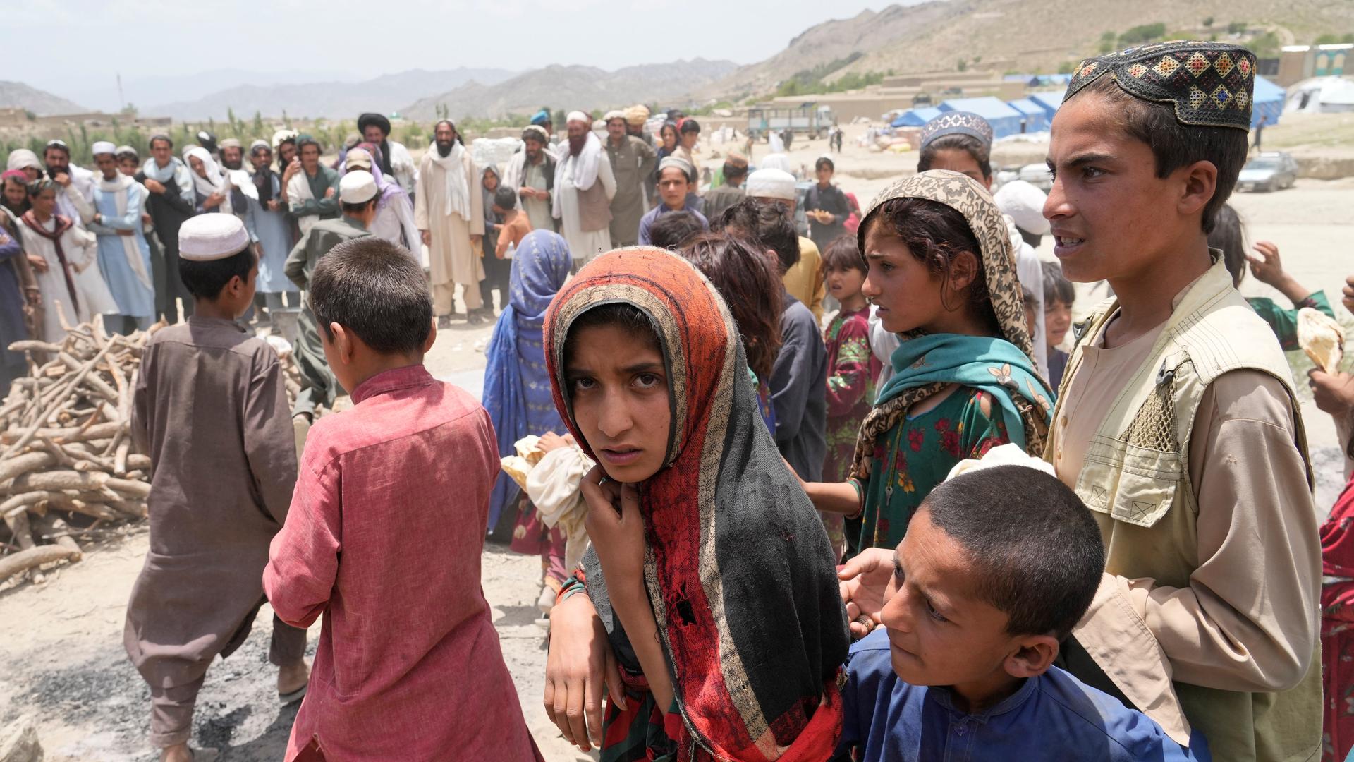 Junge Afghanen in einem Hilfscamp nach dem Erdbeben im Juni 2022: in einer Gruppe von Kindern steht in der Mitte eine junge Frau mit Kopftuch