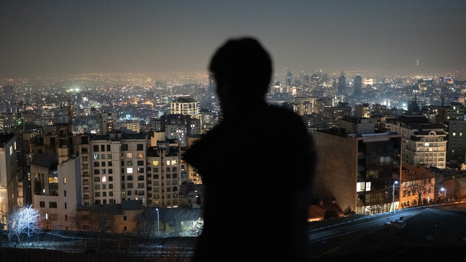 Ein Mann ist von hinten zu sehen und blickt nach Sonnenuntergang auf die Millionenmetropole Teheran. Ein Mann ist von hinten zu sehen und blickt nach Sonnenuntergang auf die Millionenmetropole Teheran.