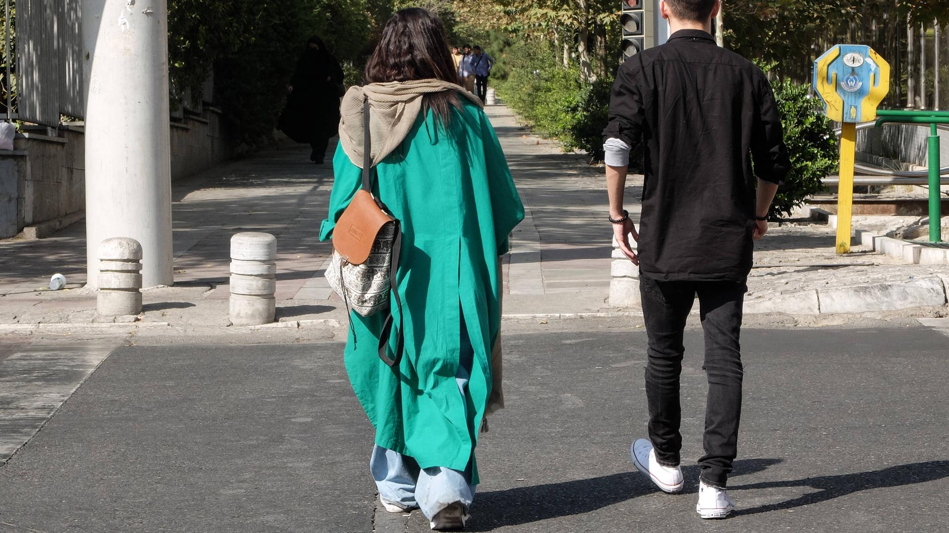 Ein junges iranisches Paar läuft auf einer Strasse in Teheran, von hinten zu sehen.