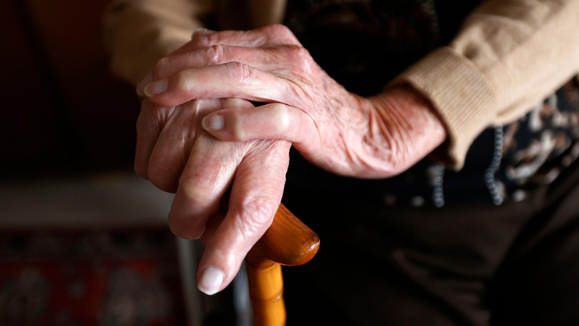 Nahaufnahme der Hände einer Seniorin, die sich an einem Gehstock festhält. Nahaufnahme der Hände einer Seniorin, die sich an einem Gehstock festhält.