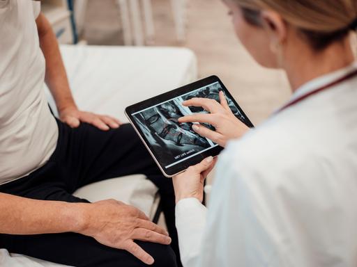 Doctor consulting with patient using tablet in medical office || Modellfreigabe vorhanden